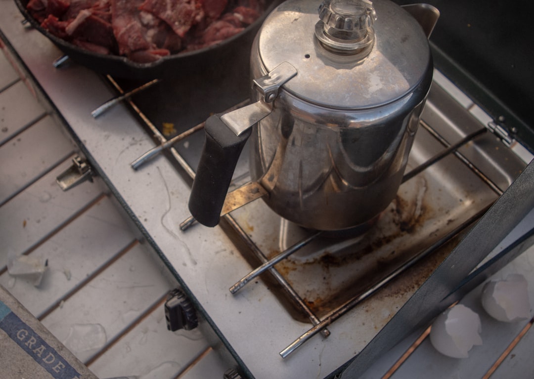 A stunning outdoor scene featuring a Soto WindMaster stove in action, cooking on a mountain trail wi