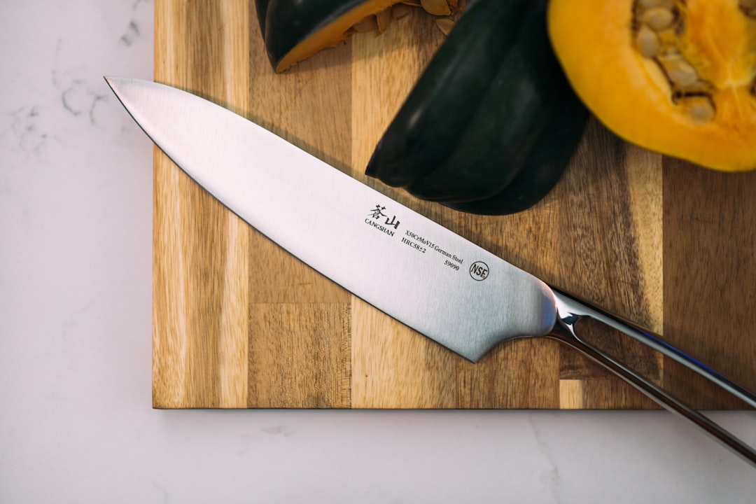 A stunning flat lay of Global and Shun chef knives on a wooden cutting board, surrounded by fresh ve