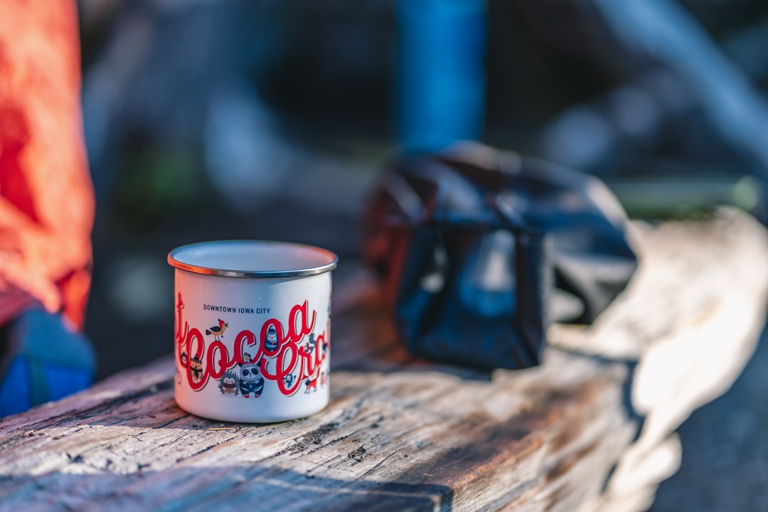 A scenic outdoor setting featuring a person enjoying a hot drink from a titanium cup while sitting b