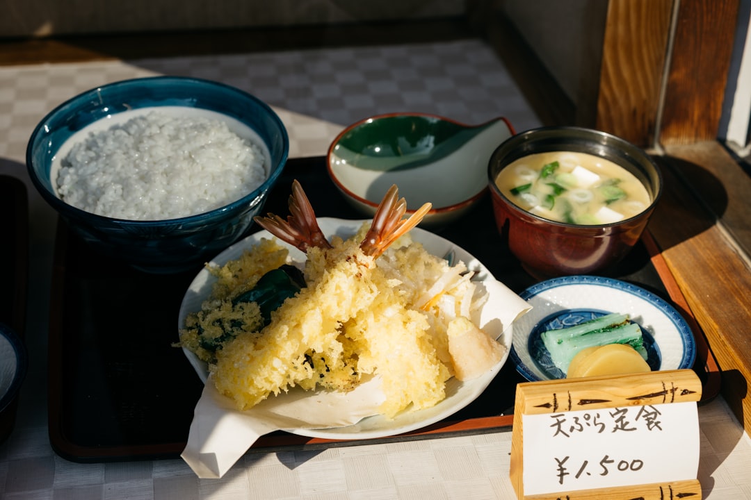 An image of a Japanese rice cooker in action, with a steaming bowl of perfectly cooked rice beside i