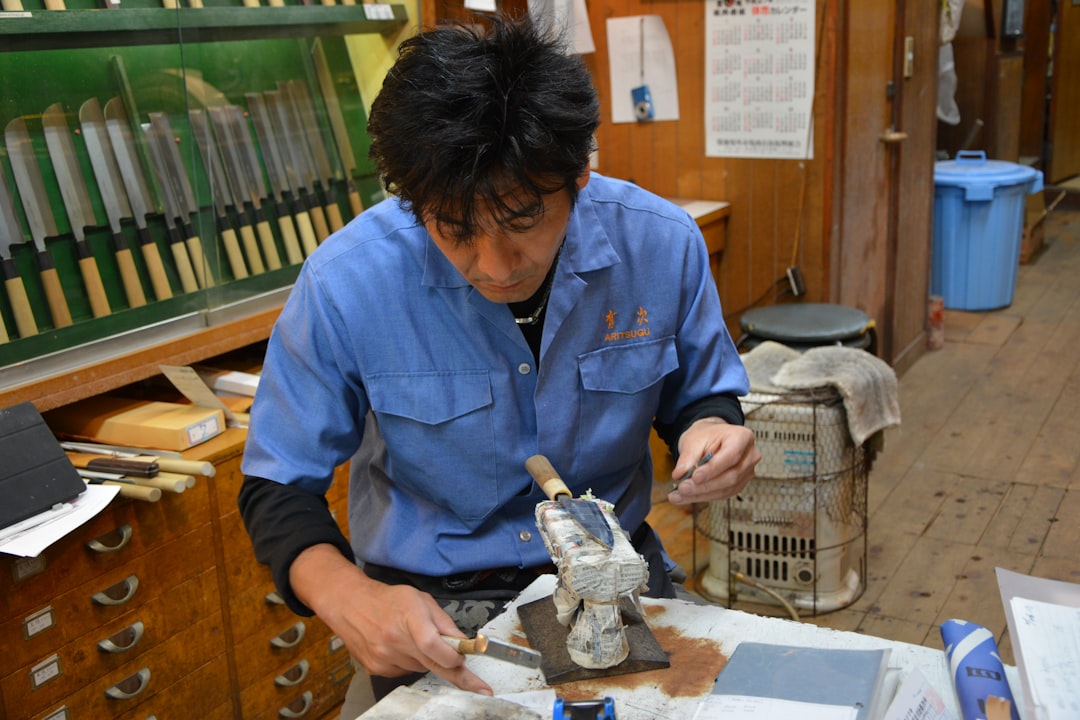 An artisan craftsman at work, hand-making a Yoshihiro knife in a traditional Japanese workshop, high
