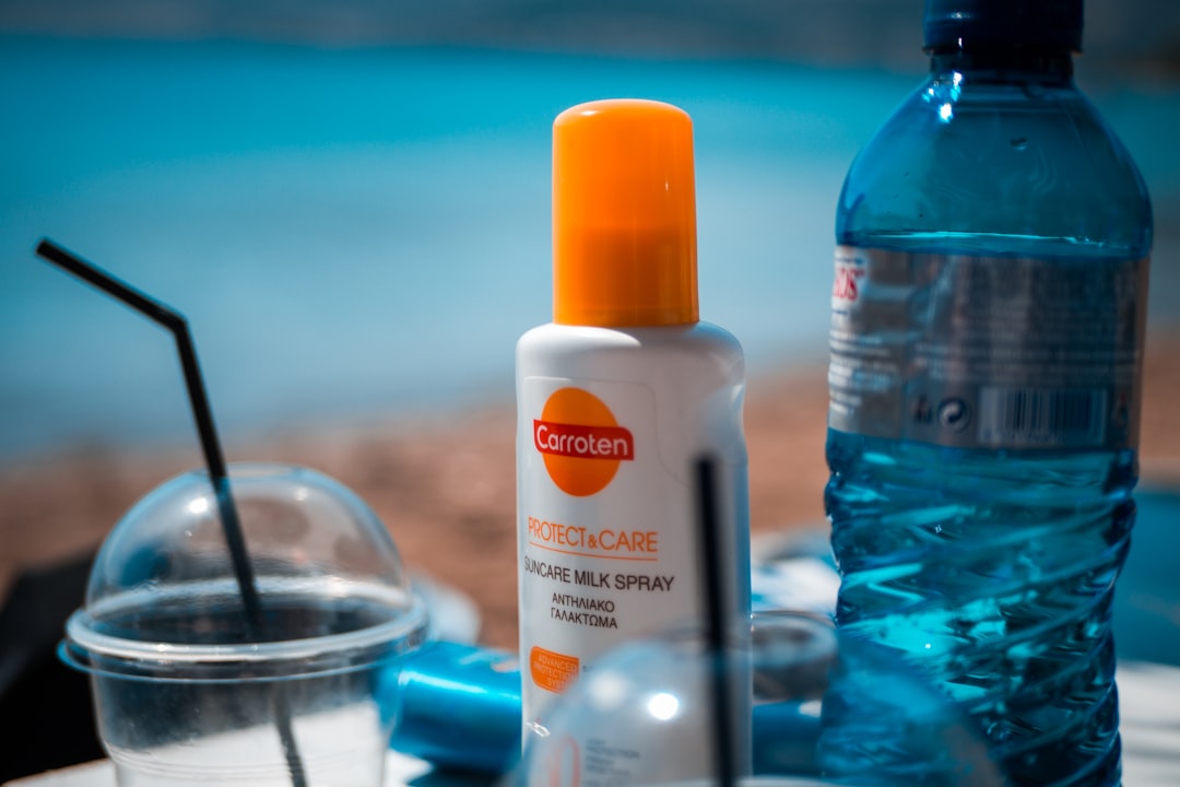 Close-up image of Biore UV Aqua Rich Watery Essence sunscreen bottle with a backdrop of summer eleme