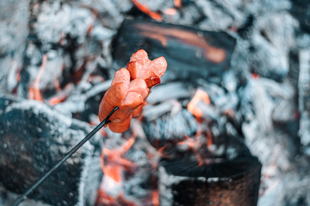 Image of a group of campers gathered around a Uniflame Stainless Steel Grill, grilling food together