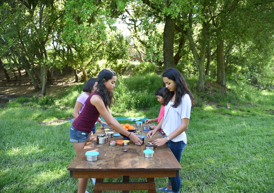 A beautifully arranged outdoor picnic scene featuring an assortment of colorful bento boxes, set aga
