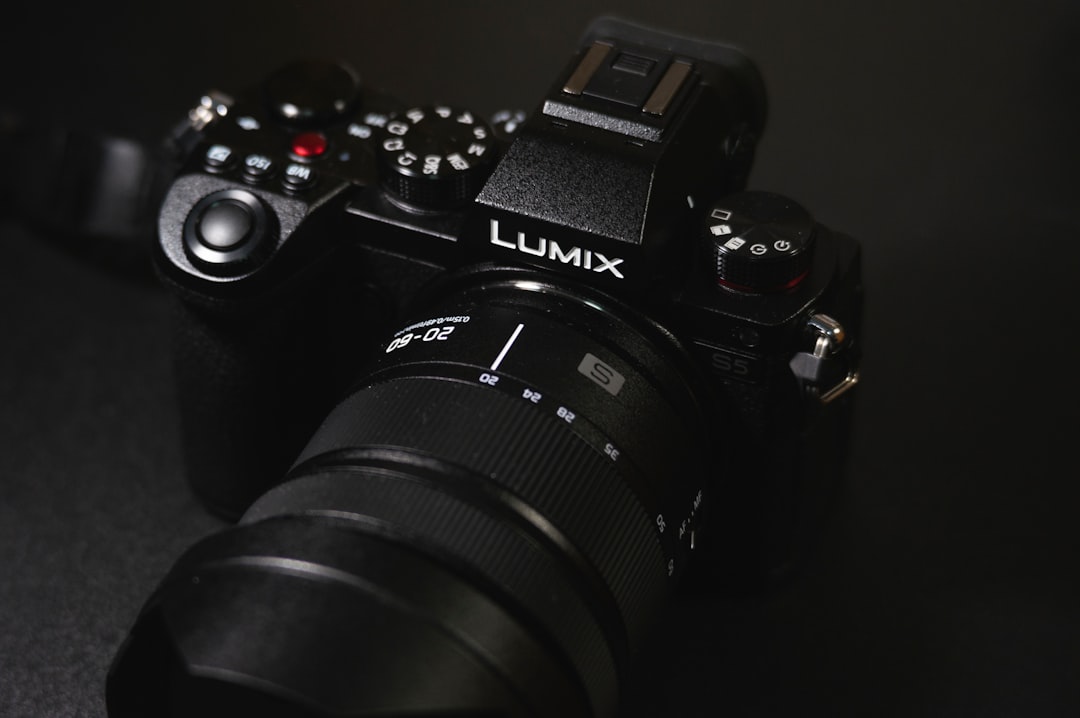 An image of the Lumix GH5 camera in an outdoor setting, with a beautiful backdrop of mountains or fo