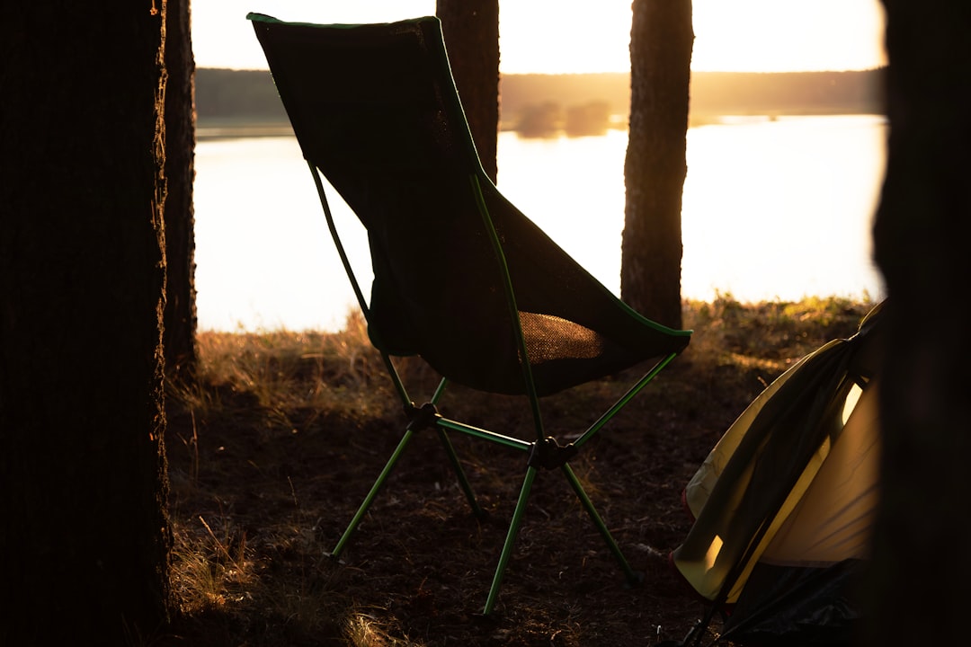 Close-up image of a Montbell Low Chair with a person sitting comfortably beside a campfire, highligh