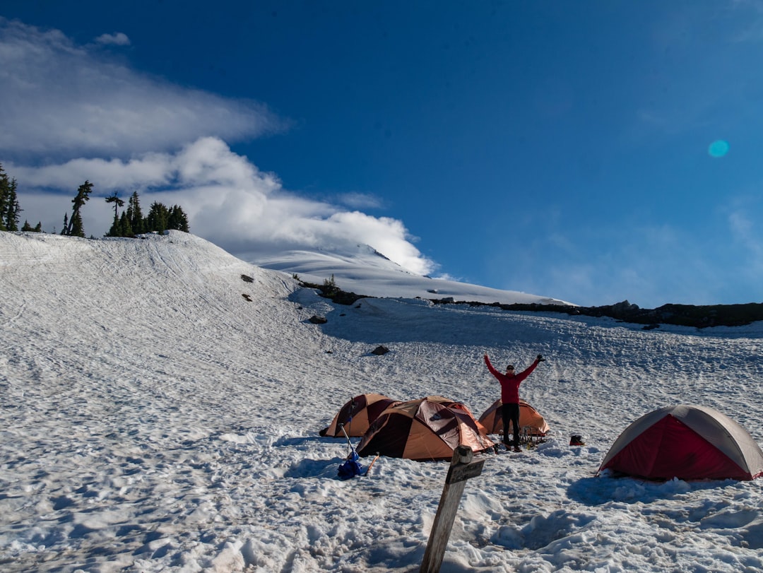 An adventurous shot of a camper using a Nanga Tsumoru 800 sleeping bag in a snowy environment, showc