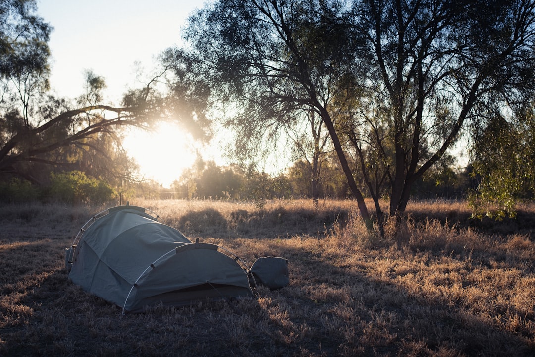 A breathtaking landscape shot featuring a serene campsite at sunrise with a Nanga sleeping bag laid