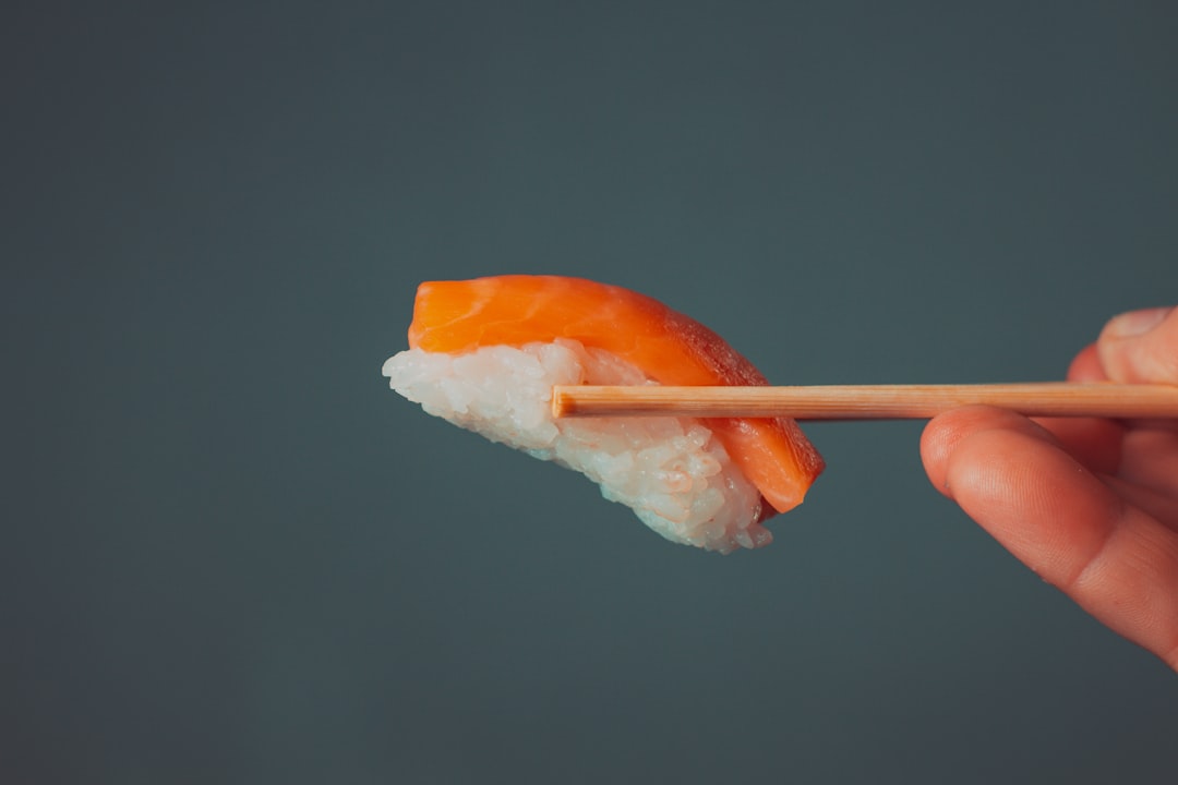An image of colorful plastic chopsticks set against a backdrop of a picnic table filled with various