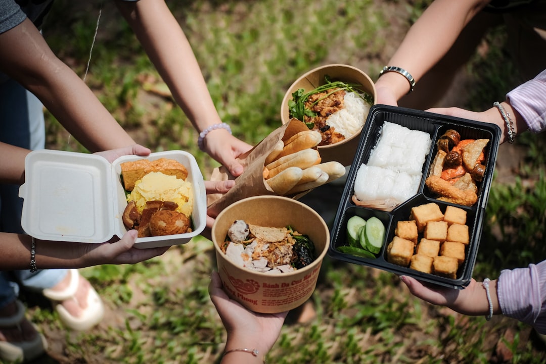 A beautifully arranged bento box filled with colorful, healthy foods set against an outdoor backdrop