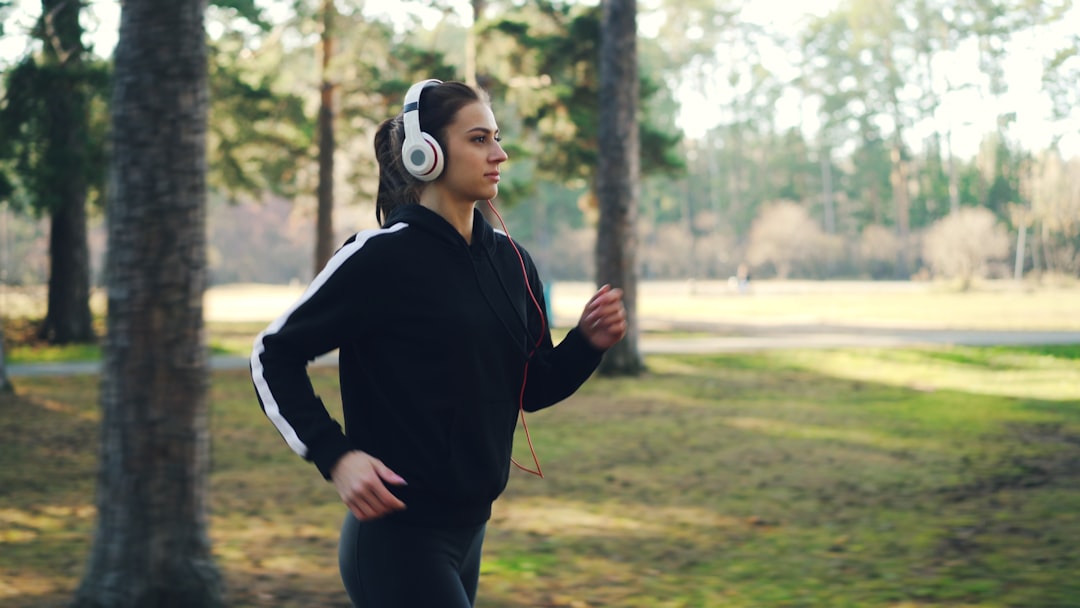 A lifestyle image of a person using Sony WF-1000XM4 earbuds while jogging in an outdoor setting, sho
