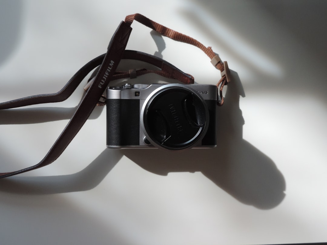 Close-up of the Fujifilm X-A7 camera on a wooden table, with a travel guide and a cup of coffee in t