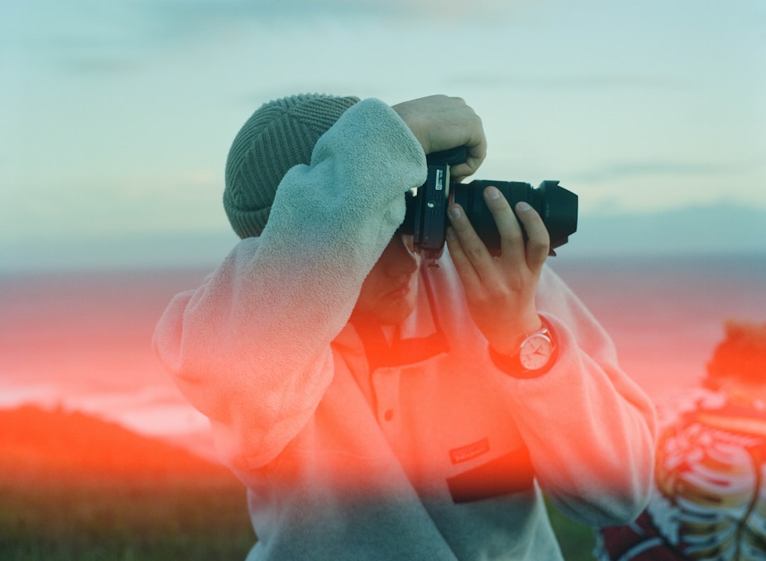 A stunning outdoor shot of a traveler using a Fujifilm or Panasonic compact camera in a picturesque
