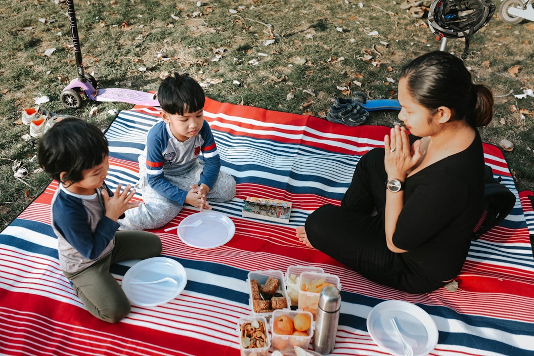 A cheerful family using the Coleman 50-Quart Performance Cooler at a family picnic, with kids playin