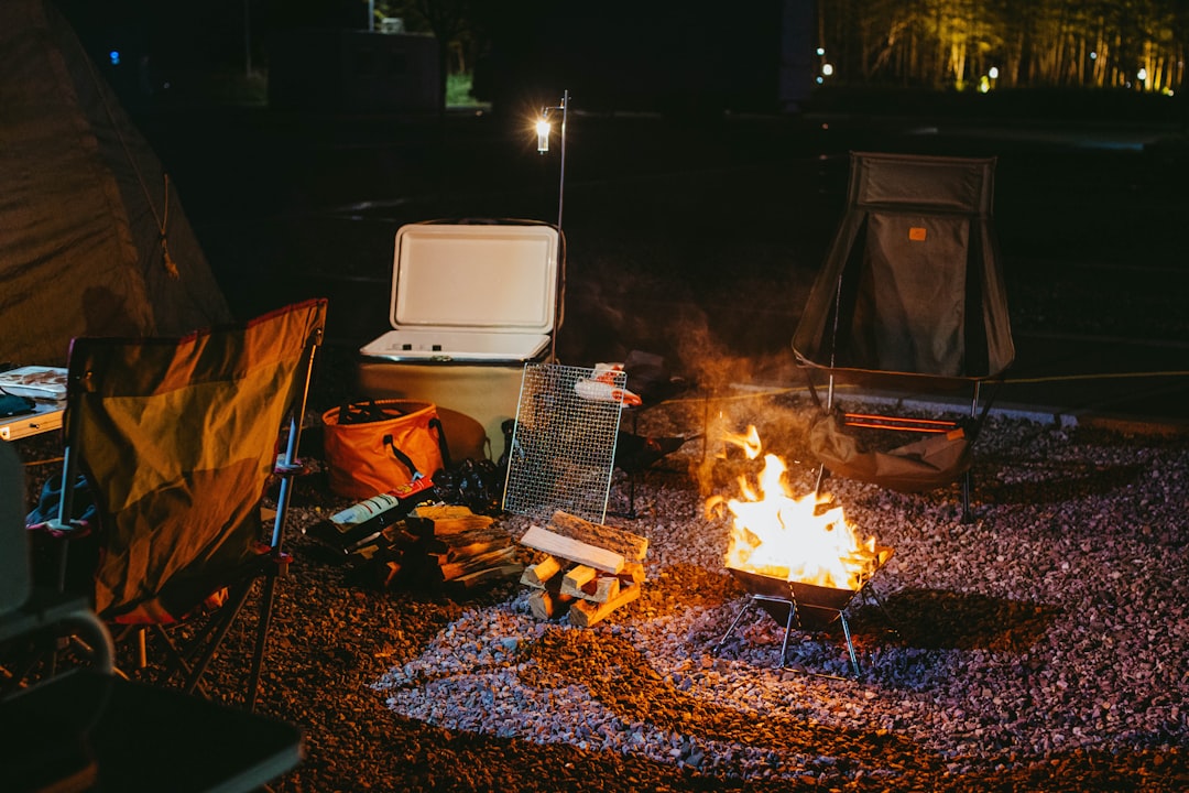 A scenic outdoor setting featuring various Japanese camping chairs set up around a campfire at dusk,