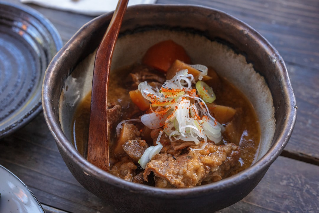 An image of the Iwachu Nambu Ironware Donabe filled with a hearty stew, highlighting its enameled in