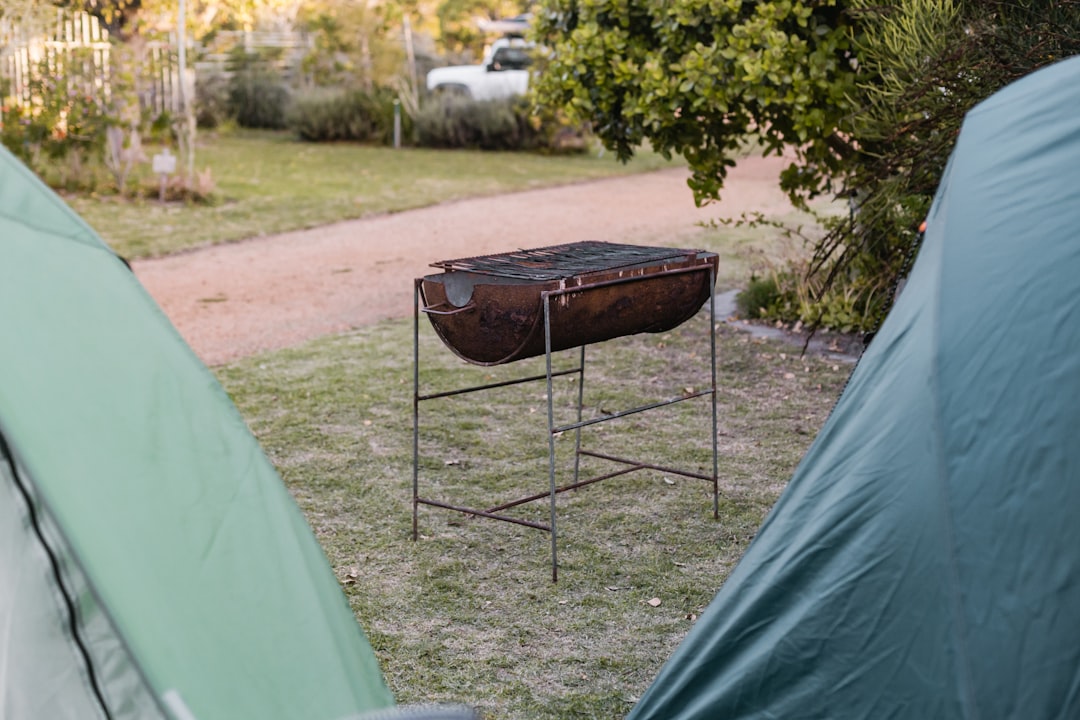 Image of a portable aluminum folding table set up at a campsite with food prep items and camping gea