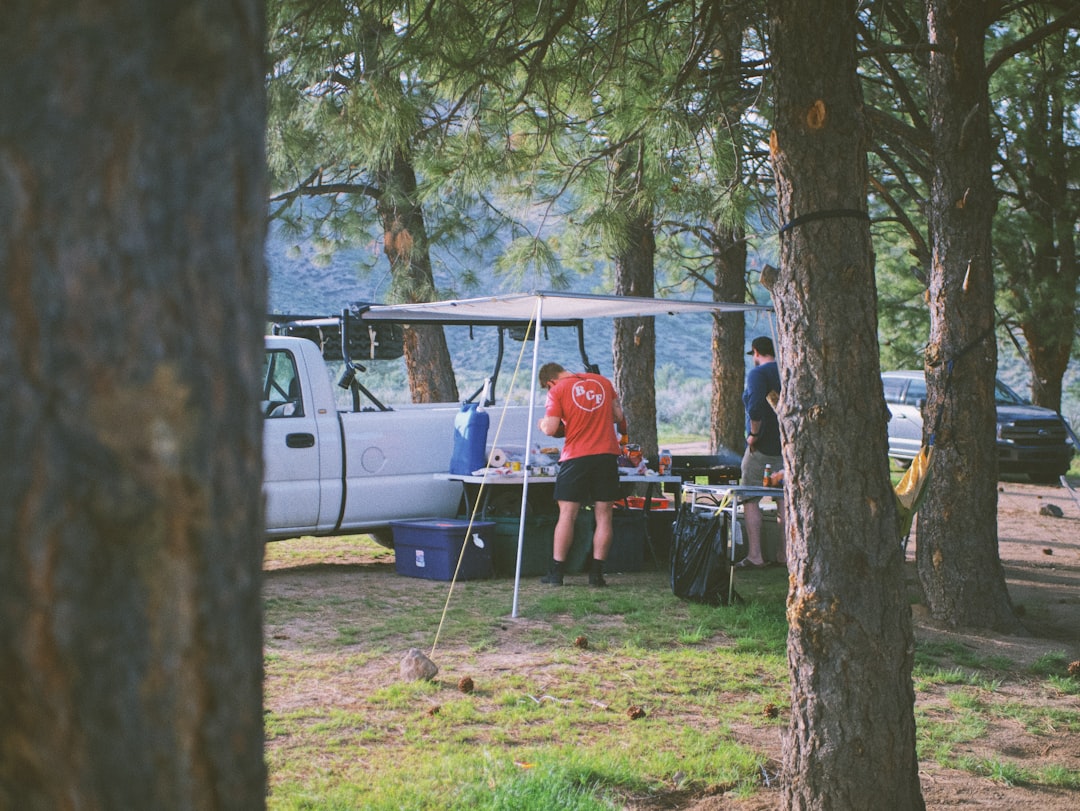 Photo of a person outdoors camping or hiking with subtle snow peak camping gear visible, applying sk