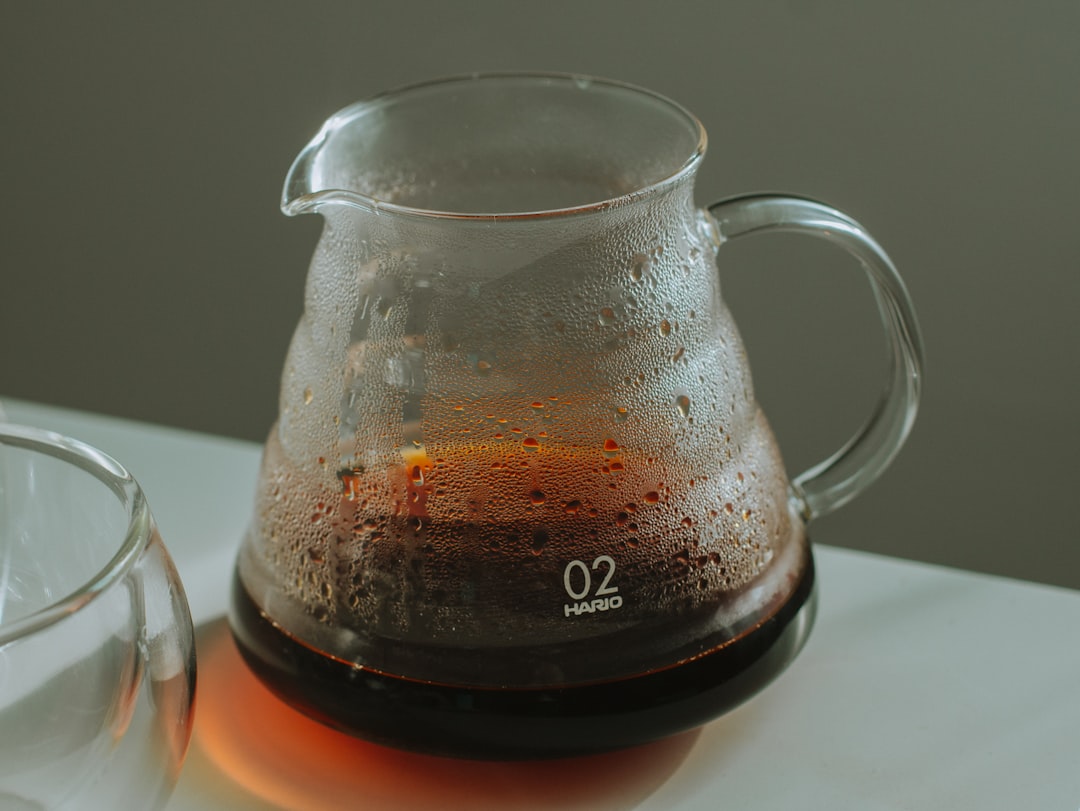 Image of a glass cold brew pot with built-in filter, filled with coffee concentrate and ice, highlig