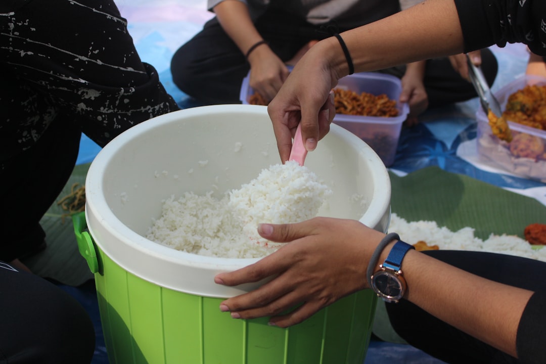 Close-up image showing the process of rinsing sushi rice in a large bowl or rice cooker inner pot, e