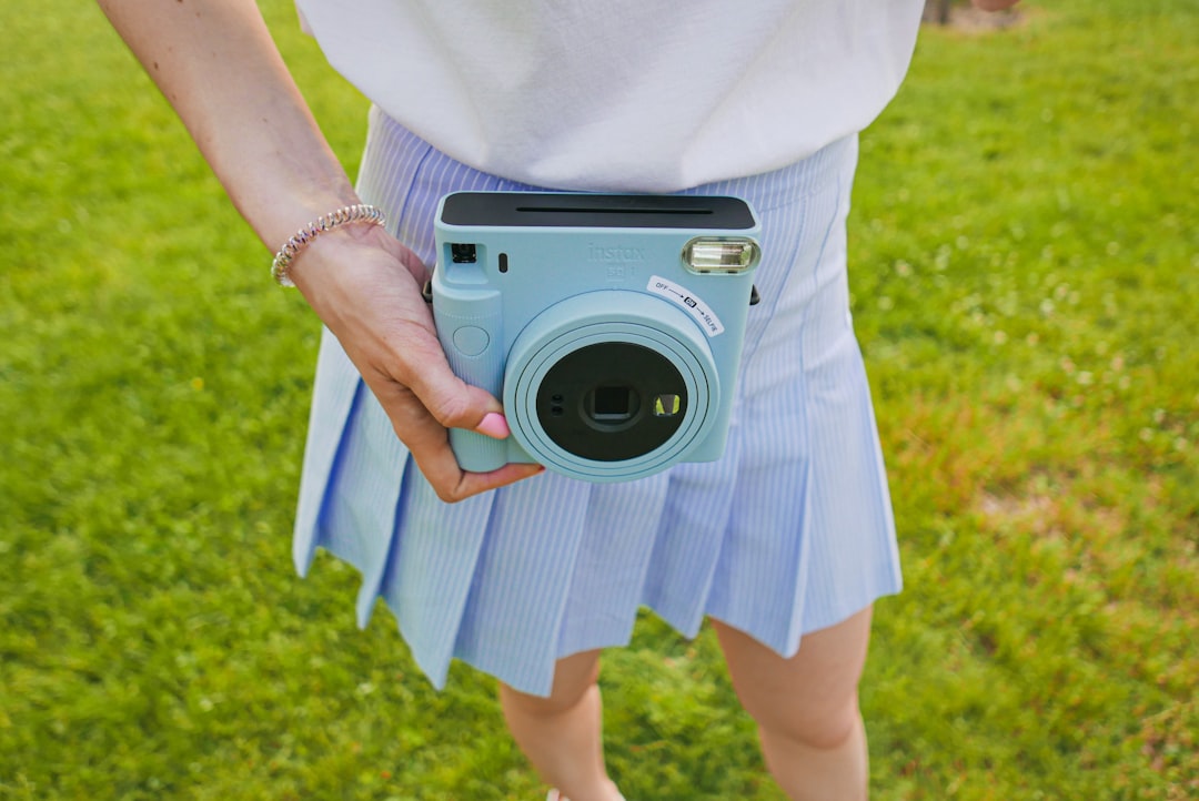 A dynamic hero image showing a Fujifilm camera (preferably an X Series mirrorless camera) held by a