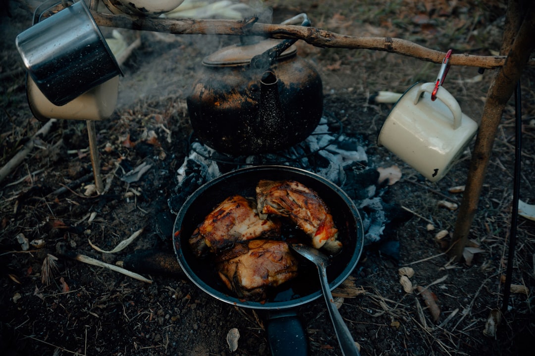 Image showing Uniflame’s stainless steel multi-pot set in use at a family campsite. The cookware sho