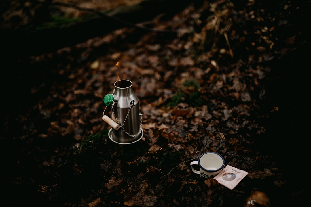 A high-quality hero image featuring a Japanese titanium camping cup outdoors on a rustic wooden tabl