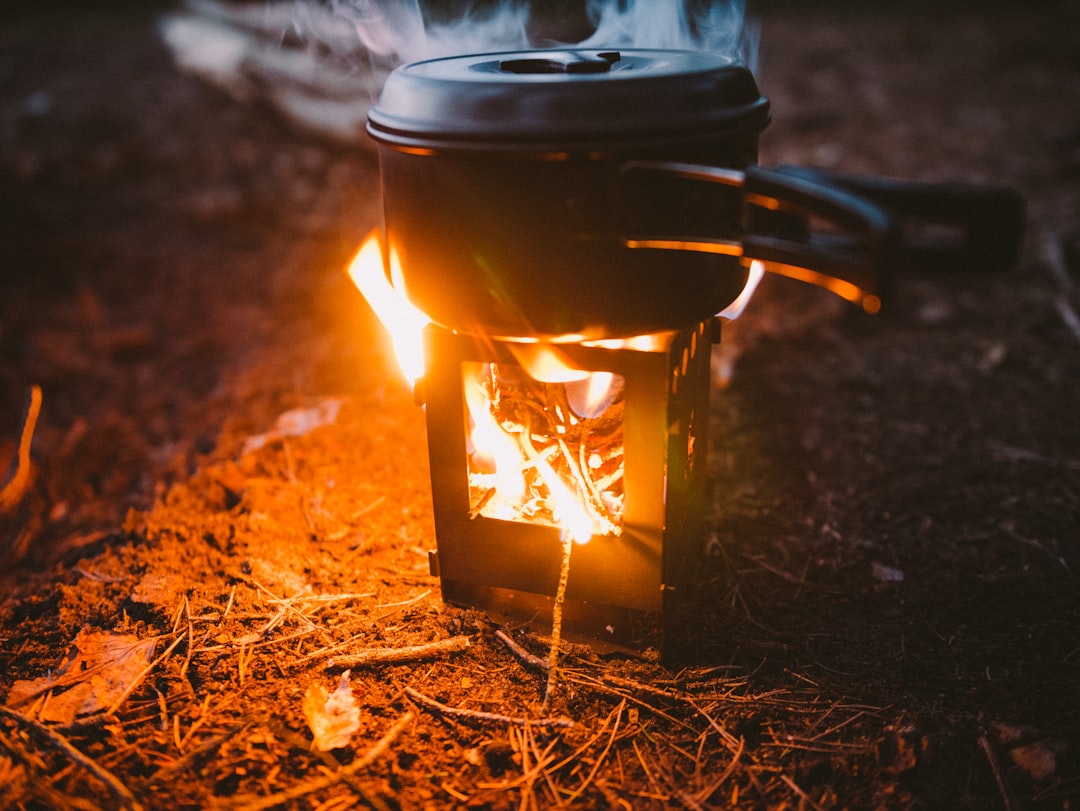 Hero image showing a Soto WindMaster stove in action with a visible flame, set on a rocky or forest