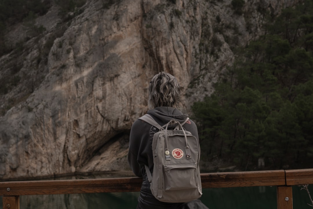 Photo of a hiker or camper holding a titanium cup (such as the Sori Titanium Cup) clipped to a backp