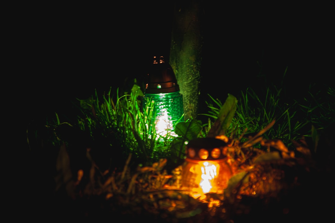 Photo showing a Snow Peak Takibi Lantern burning brightly next to a campfire with a backpacker setti