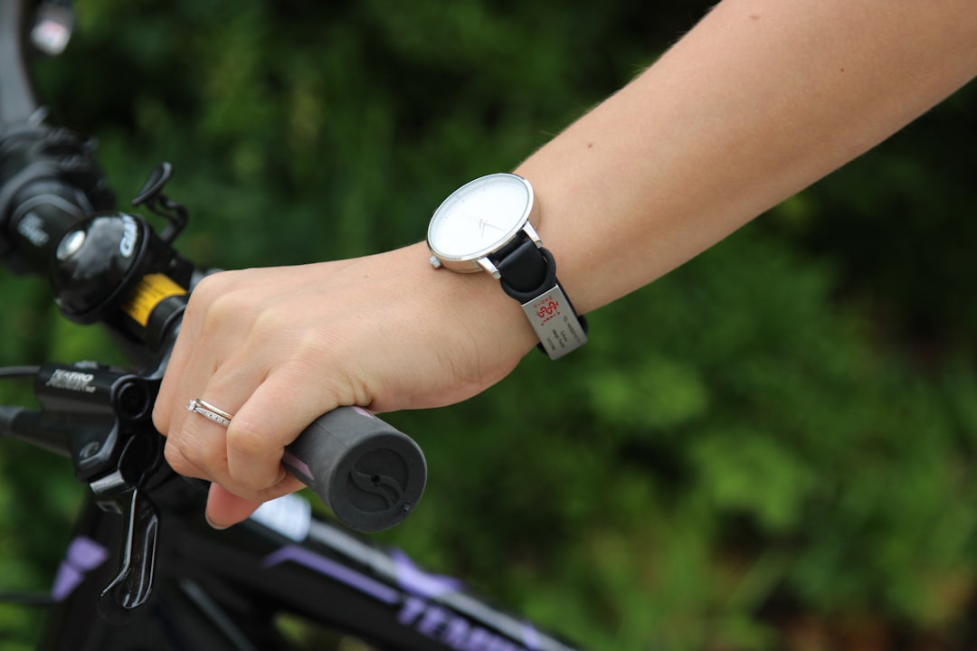 Image showing a person using a smartwatch with built-in GPS while cycling on a scenic outdoor trail,
