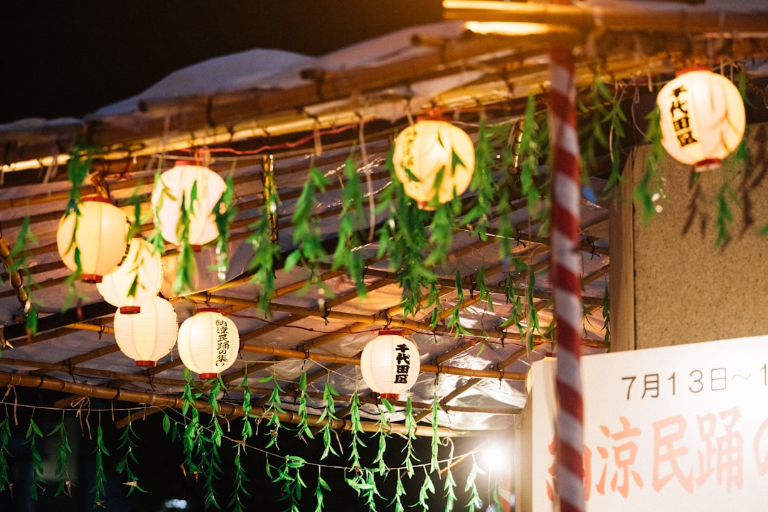 A warm, inviting nighttime campsite scene featuring both Soto and Coleman Japan lanterns illuminated