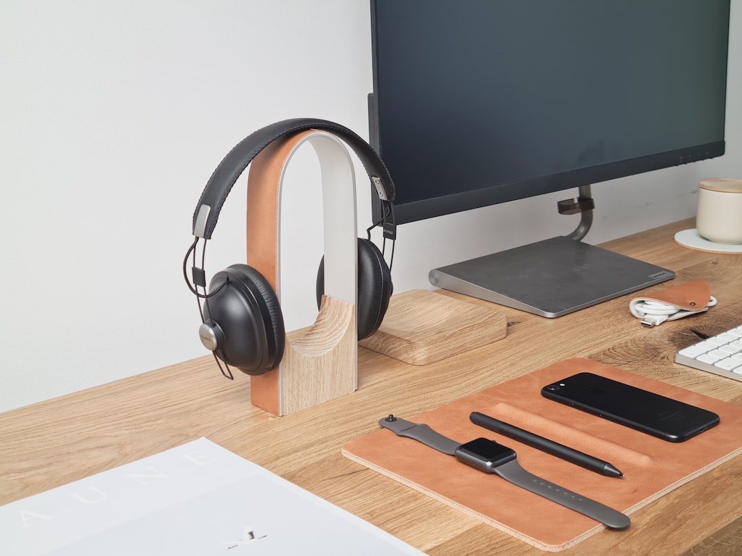 Image of Sony WH-1000XM5 wireless headphones on a desk next to a smartphone and laptop, highlighting