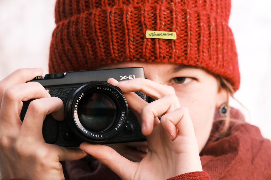 Close-up photo of a Fujifilm X-Series camera (e.g., X-S10 or X-T30 II) on a wooden table or in hand,