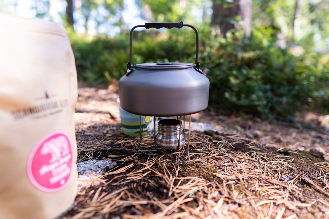 Image of the Hario Skerton Pro manual grinder being used outdoors on a camping table, with a scenic 