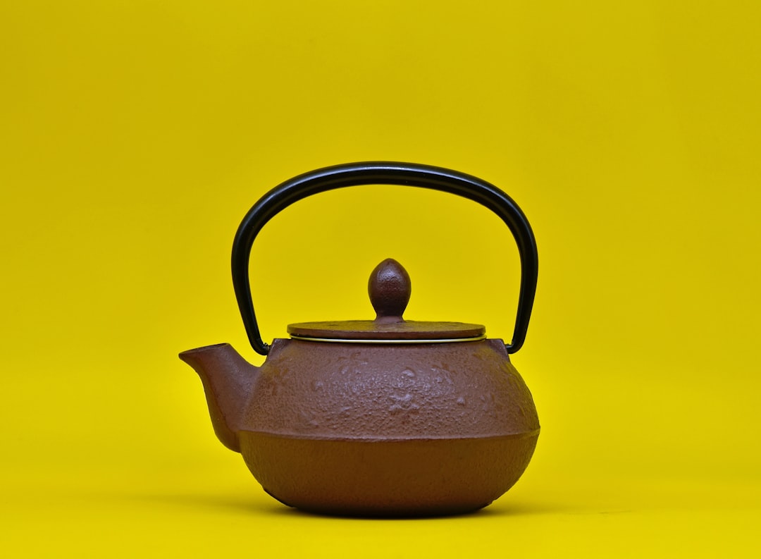 Image showcasing the Tiger Tetsubin-style cast iron teapot on a wooden table with steam rising, alon